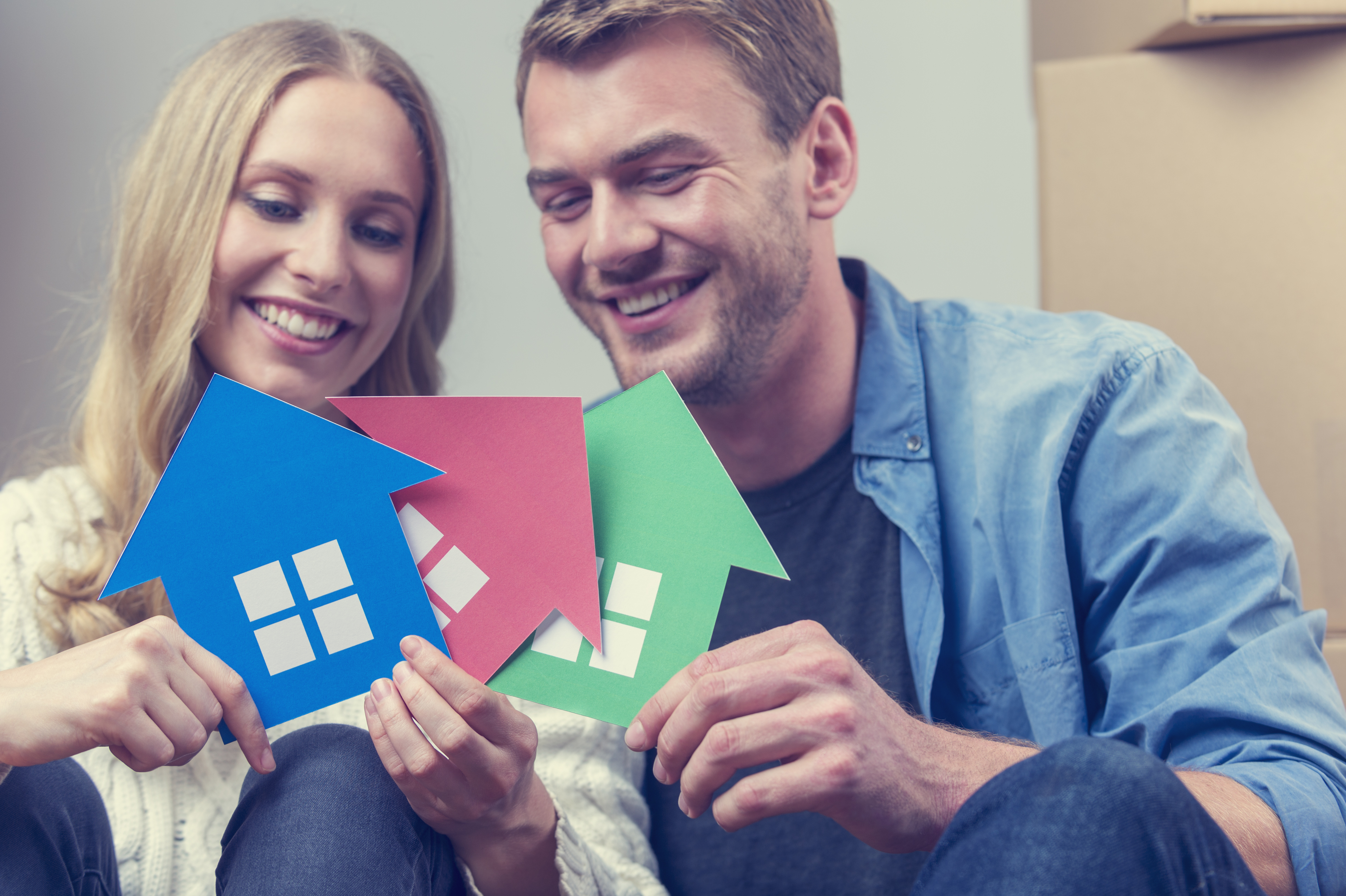 couple holding cutout pictures of houses